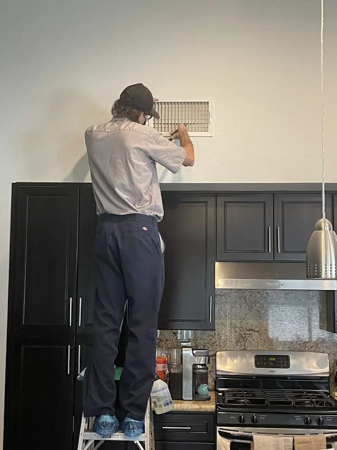 Technician inspecting an air vent during HVAC service in Lewiston